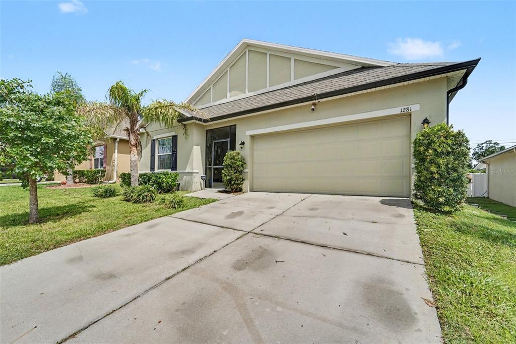 A single-story house with a beige stucco exterior, a two-car garage, and a concrete driveway — 1281 WATER WILLOW DRIVE, GROVELAND, FL