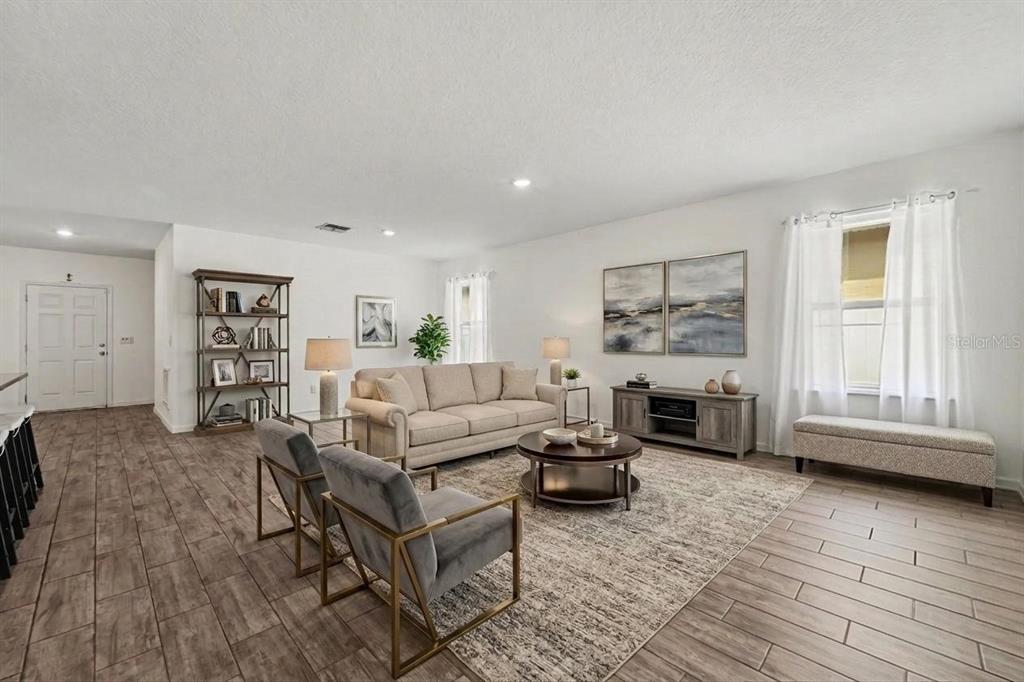 A living room features light tile flooring, a beige sofa, two grey chairs, and artwork — 1281 WATER WILLOW DRIVE, GROVELAND, FL