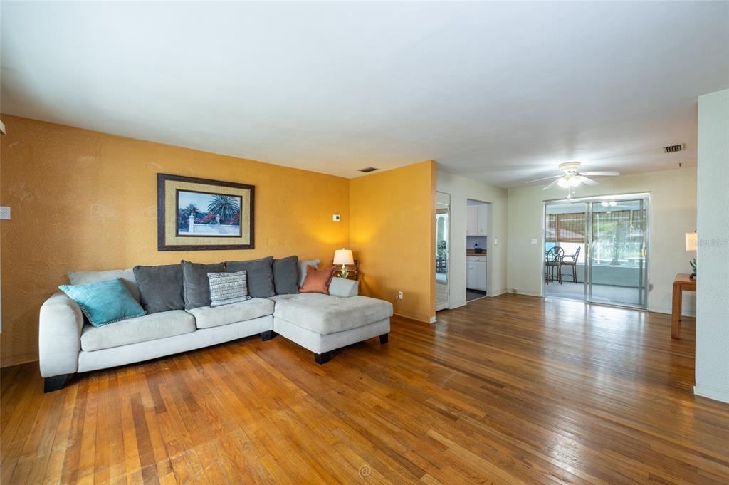 A living room features hardwood floors, a sectional sofa, and a yellow accent wall — 1256 BEL AIRE DRIVE, DAYTONA BEACH, FL