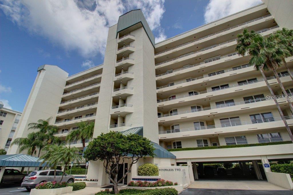 A low-angle exterior view of the multi-story Windwards Two condominium building with palm trees — 7932 SAILBOAT KEY BOULEVARD S UNIT 504, SOUTH PASADENA, FL