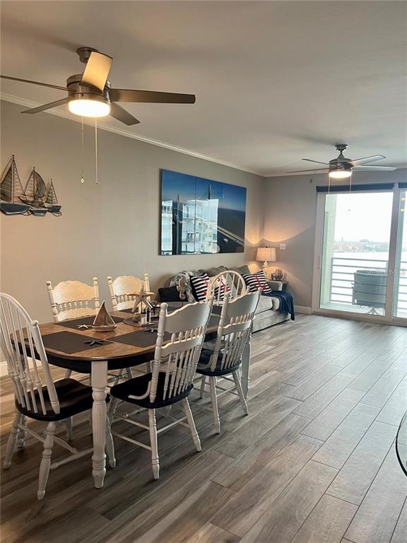 A dining area and living room with wood-look tile flooring and two ceiling fans — 7932 SAILBOAT KEY BOULEVARD S UNIT 504, SOUTH PASADENA, FL