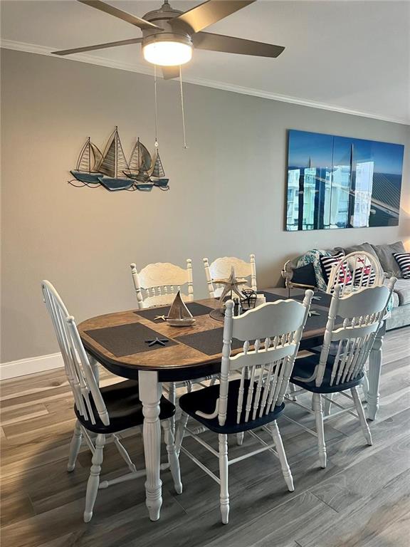 A dining area features a wooden table with white chairs, a ceiling fan, and wall decor — 7932 SAILBOAT KEY BOULEVARD S UNIT 504, SOUTH PASADENA, FL