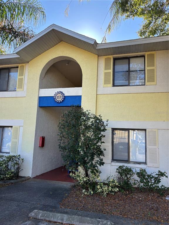 A two-story apartment building exterior features yellow stucco walls, blue accents, and a covered entryway — 90 HIDDEN LAKE DRIVE UNIT 178, SANFORD, FL