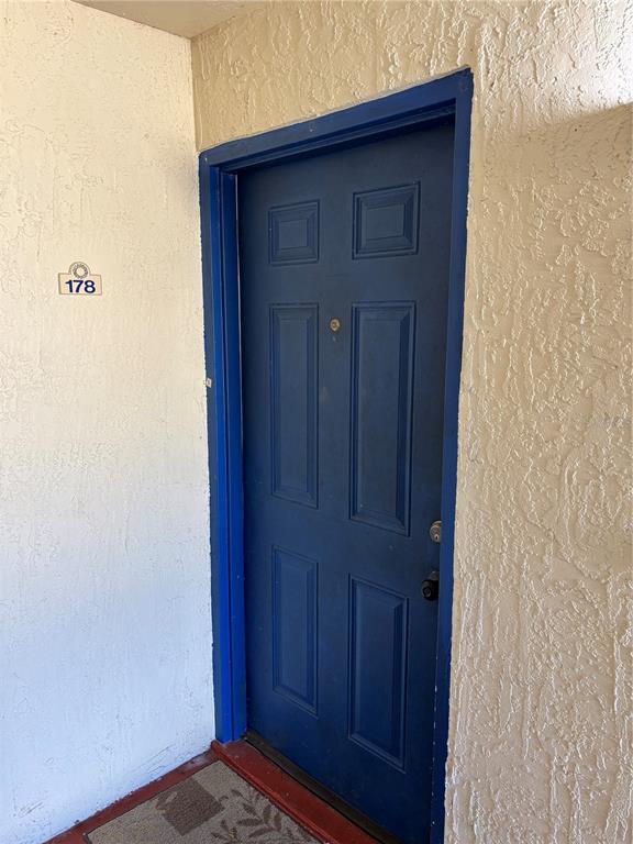 A blue front door with a number 178 sign on a textured white exterior wall — 90 HIDDEN LAKE DRIVE UNIT 178, SANFORD, FL
