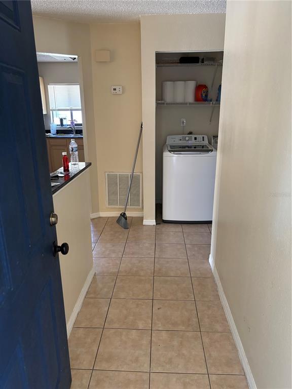 A tiled entryway leads to a laundry closet with a washing machine and kitchen view — 90 HIDDEN LAKE DRIVE UNIT 178, SANFORD, FL