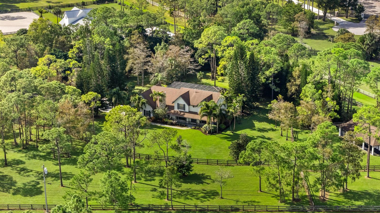 An aerial view shows a two-story house surrounded by trees, lawns, and fenced pastures — 5371 Cougars Prowl, Lake Worth FL 33449, LAKE WORTH, FL