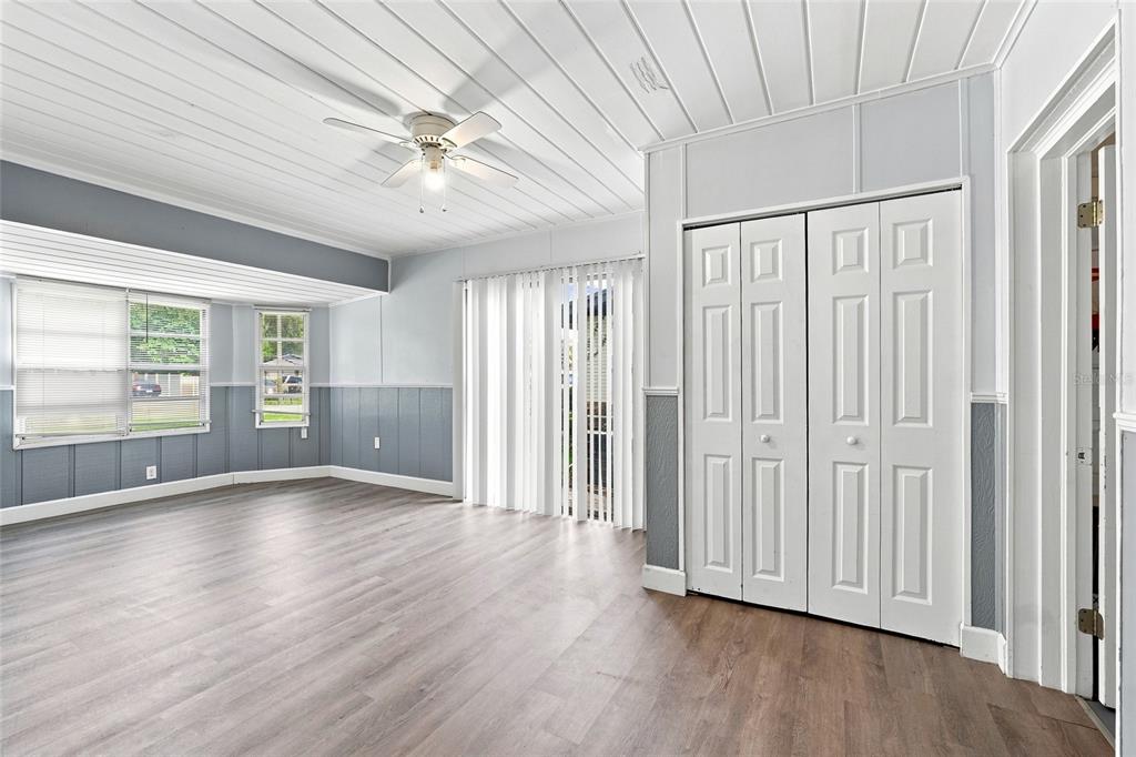 A living room features light wood-look flooring, blue wainscoting, white paneled walls, and a ceiling fan — 1024 31ST STREET NW, WINTER HAVEN, FL
