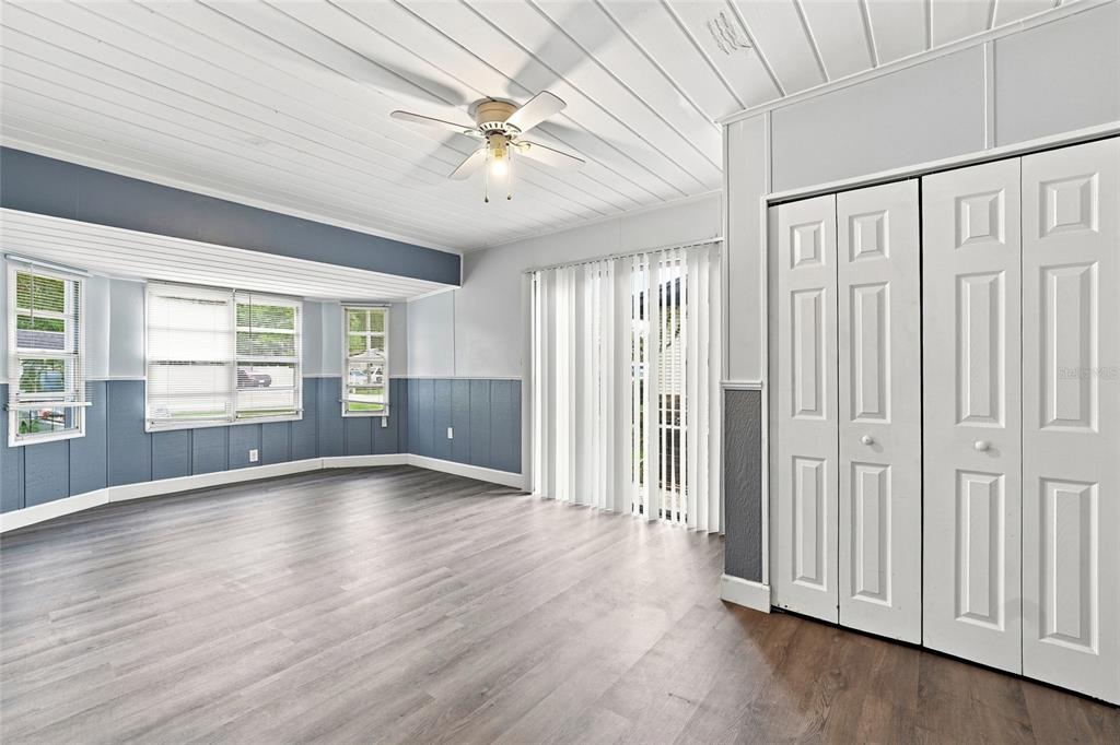A living room features wood-look flooring, blue wainscoting, a ceiling fan, and white closet doors — 1024 31ST STREET NW, WINTER HAVEN, FL