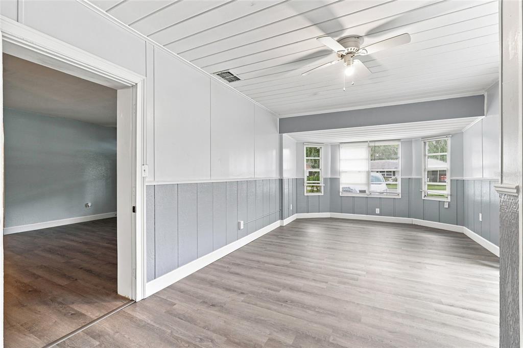 A living room with gray and white paneled walls, wood-look flooring, and a ceiling fan — 1024 31ST STREET NW, WINTER HAVEN, FL