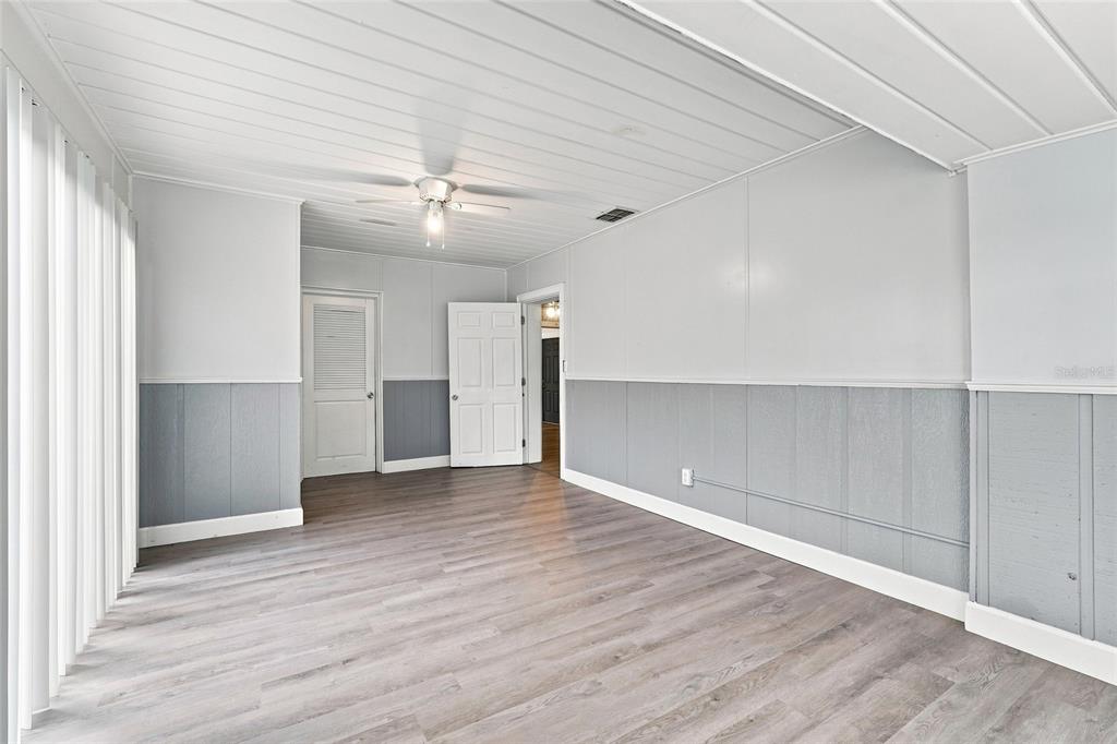 A room with gray wood-look flooring, white paneled walls, and a white plank ceiling — 1024 31ST STREET NW, WINTER HAVEN, FL