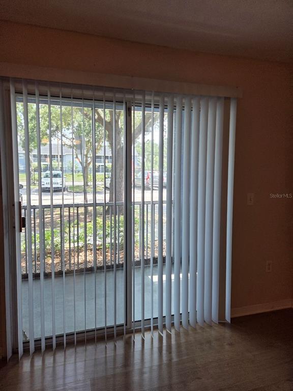 A room with light wood-look flooring features a sliding glass door with white vertical blinds — 5824 LAKE POINTE VILLAGE CIRCLE UNIT 504, ORLANDO, FL
