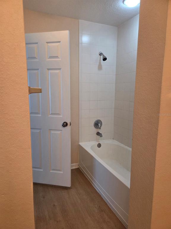 A bathroom features a white bathtub with a shower head and tiled walls — 5824 LAKE POINTE VILLAGE CIRCLE UNIT 504, ORLANDO, FL