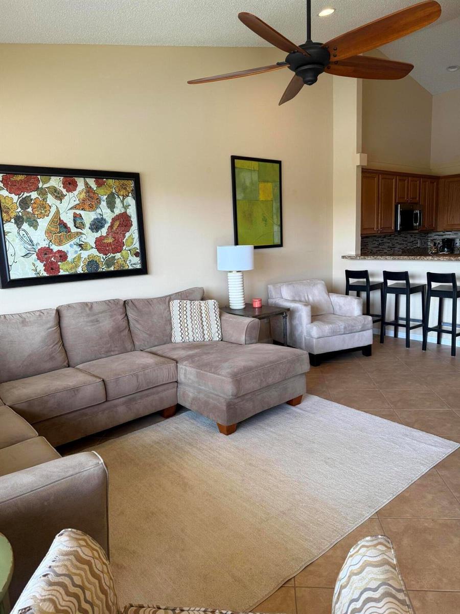 A living room features a sectional sofa, an armchair, and a kitchen breakfast bar — 227 Coral Trace Lane # 227, Delray Beach FL 33445, DELRAY BEACH, FL