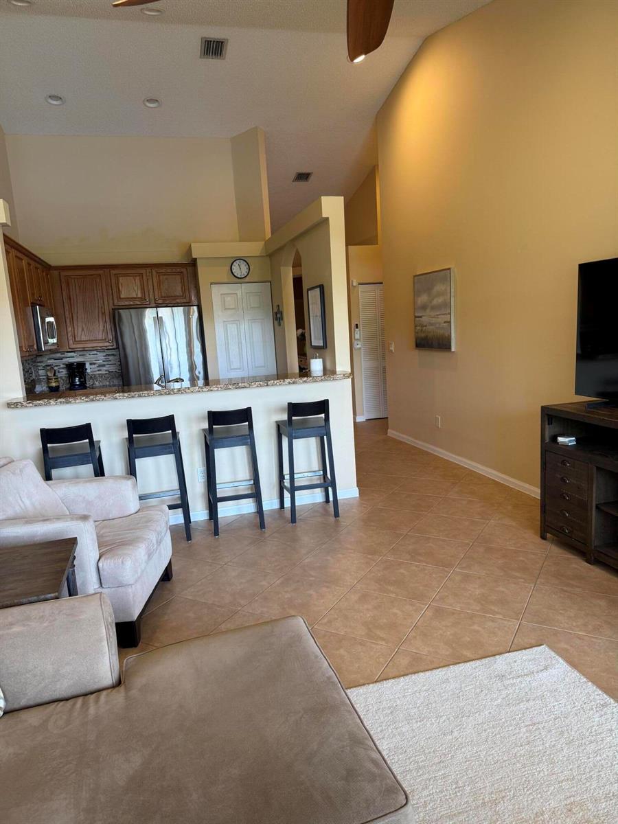 A living room with tile floors opens to a kitchen featuring a breakfast bar — 227 Coral Trace Lane # 227, Delray Beach FL 33445, DELRAY BEACH, FL