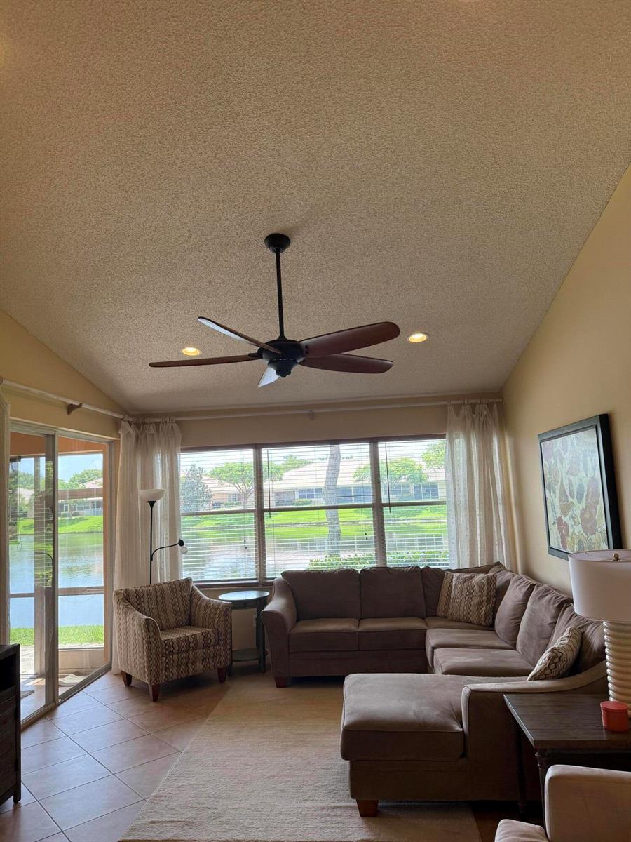 A living room with a vaulted ceiling, ceiling fan, sectional sofa, and lake view windows — 227 Coral Trace Lane # 227, Delray Beach FL 33445, DELRAY BEACH, FL