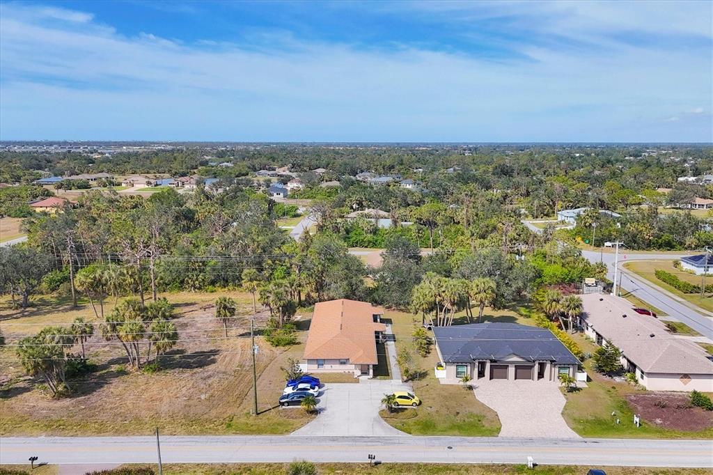 An aerial view shows two suburban houses with driveways along a road surrounded by trees — 355 BOUNDARY BOULEVARD UNIT C, ROTONDA WEST, FL