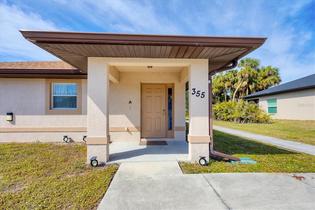 The exterior of a single-story house features a covered entryway with a tan front door — 355 BOUNDARY BOULEVARD UNIT C, ROTONDA WEST, FL