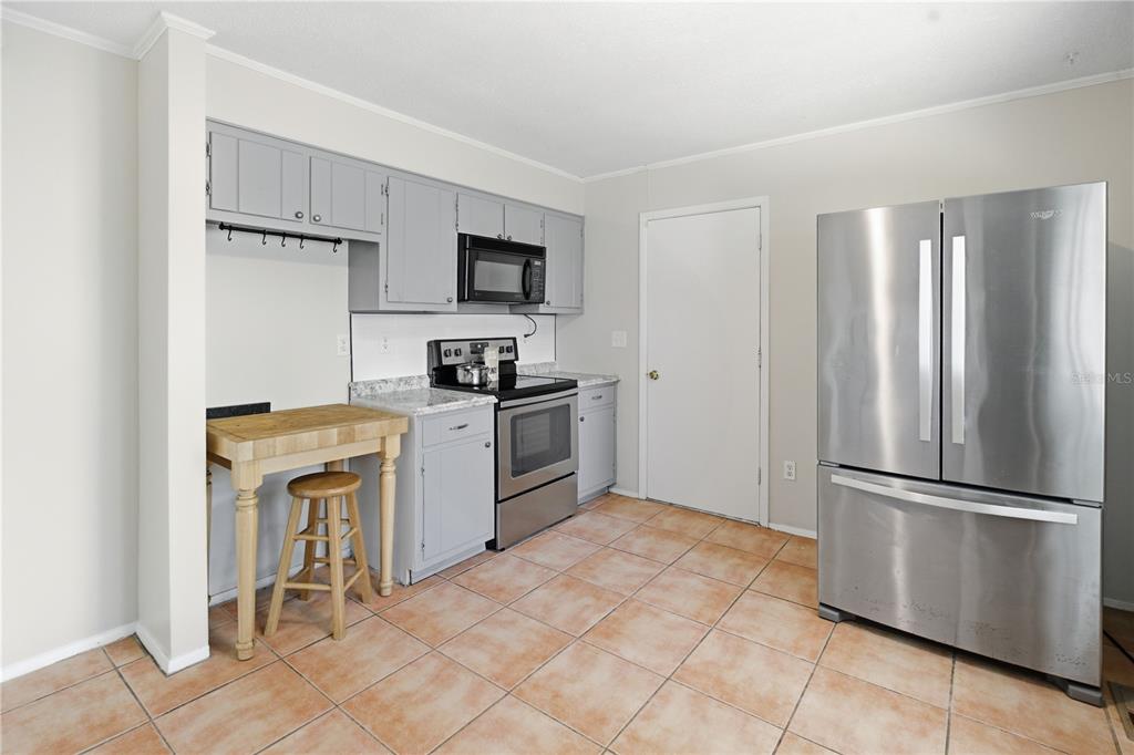 A kitchen features gray cabinets, stainless steel appliances, a wooden island, and tiled flooring — 100 N HIGHLAND AVENUE, GREEN COVE SPRINGS, FL