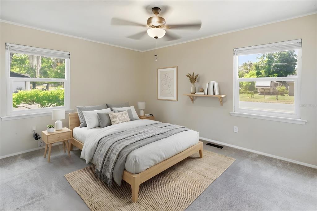 A bedroom features a wooden bed frame, two windows, a ceiling fan, and neutral decor — 100 N HIGHLAND AVENUE, GREEN COVE SPRINGS, FL