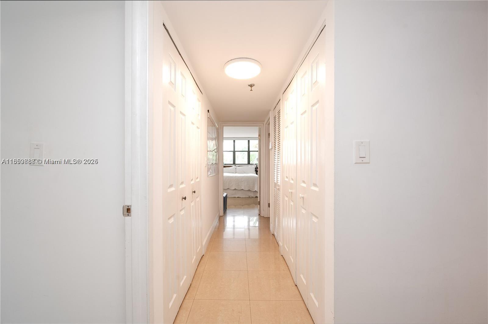 A hallway with white paneled closet doors leads to a bedroom with a window — 1621 Collins Ave # 302, Miami Beach FL 33139, MIAMI BEACH, FL