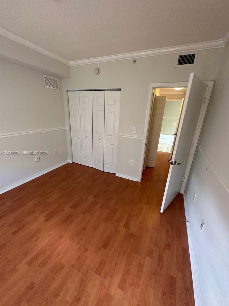 This room features wood-look flooring, white walls with chair rail molding, and a closet — CUTLER BAY, FL