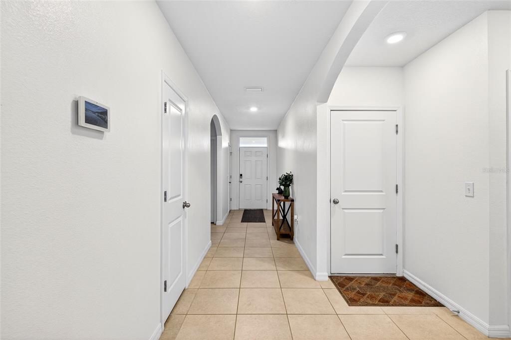 A bright hallway with light tile flooring leads to a white front door — 2530 NE 42ND ROAD, OCALA, FL