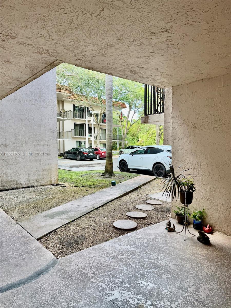 A view from a covered patio looking out toward a parking lot and apartment building — 4725 SW 62nd Ave # 104, Davie FL 33314, DAVIE, FL