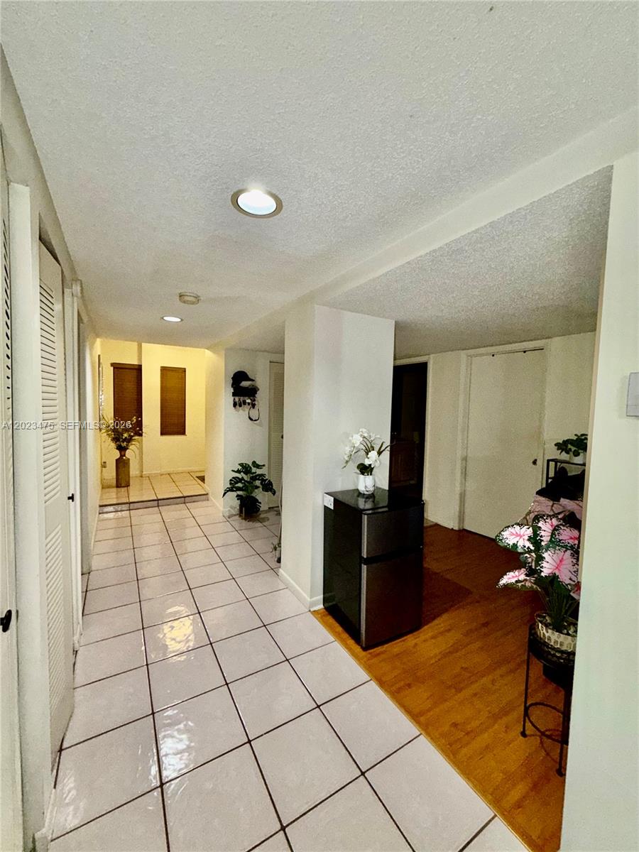 A hallway features white tiled flooring, a wooden floor section, and a small refrigerator — 4725 SW 62nd Ave # 104, Davie FL 33314, DAVIE, FL
