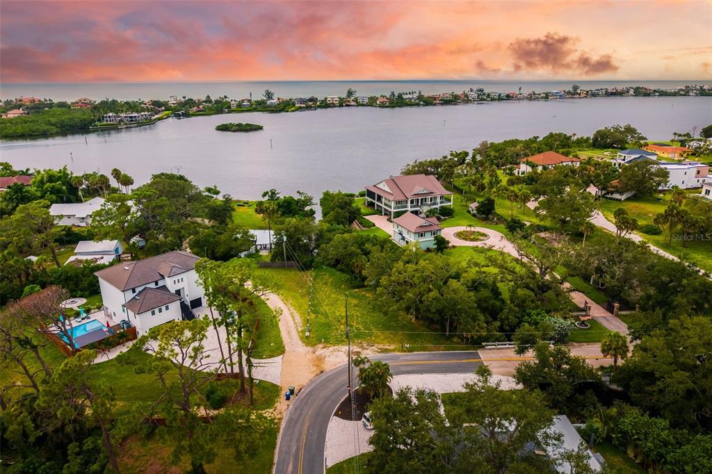 An aerial view shows two waterfront houses with pools and driveways near a large bay — OAK STREET, NOKOMIS, FL