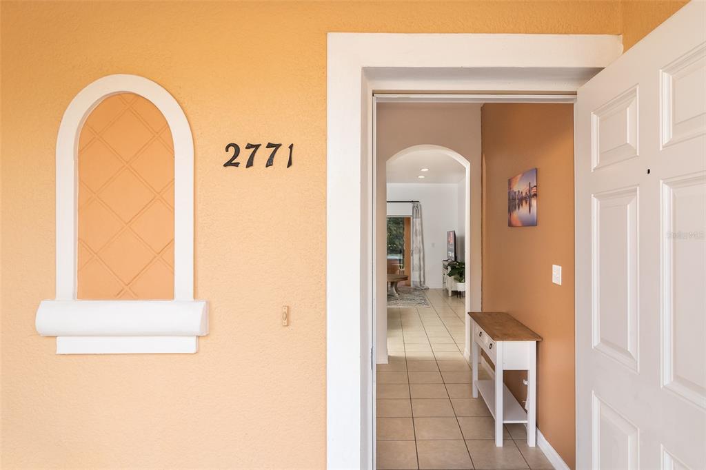 The view shows an open front door leading into a tiled entryway with a console table — 2771 CORVETTE LANE, KISSIMMEE, FL
