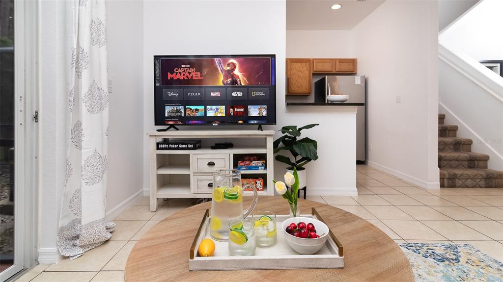 A living room features a television on a white console, a round coffee table, and stairs — 2771 CORVETTE LANE, KISSIMMEE, FL