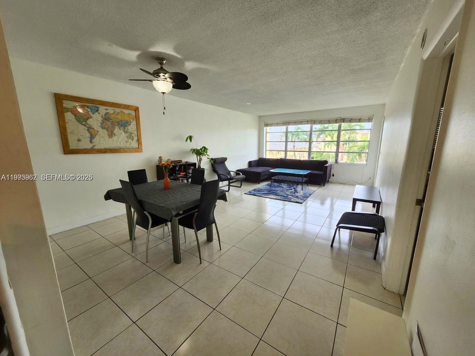 A dining and living area features tile flooring, a ceiling fan, and a world map — 851 NE 14th Ave # 420, Hallandale Beach FL 33009, HALLANDALE BEACH, FL