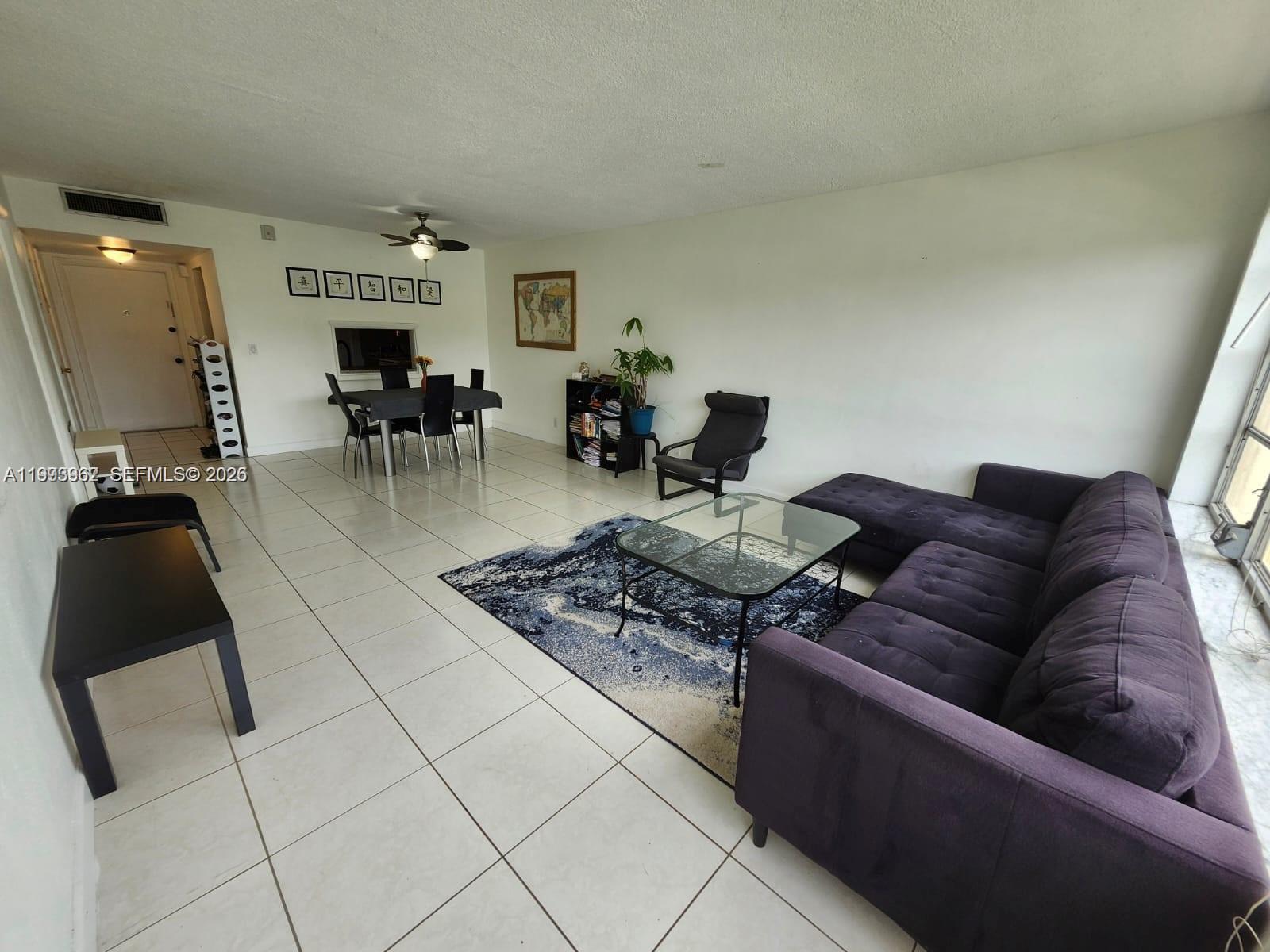 A living and dining area features white tile floors, a dark sectional sofa, and furniture — 851 NE 14th Ave # 420, Hallandale Beach FL 33009, HALLANDALE BEACH, FL