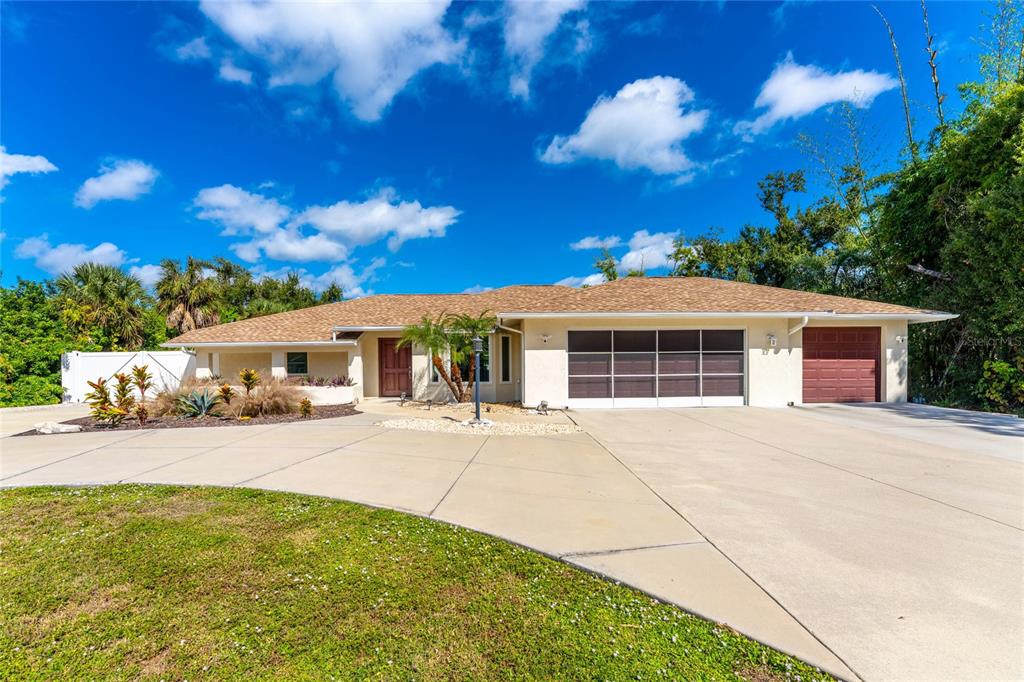 A single-story house with a tan exterior, a large concrete driveway, and a brown roof — 1600 THOMAS STREET, ENGLEWOOD, FL