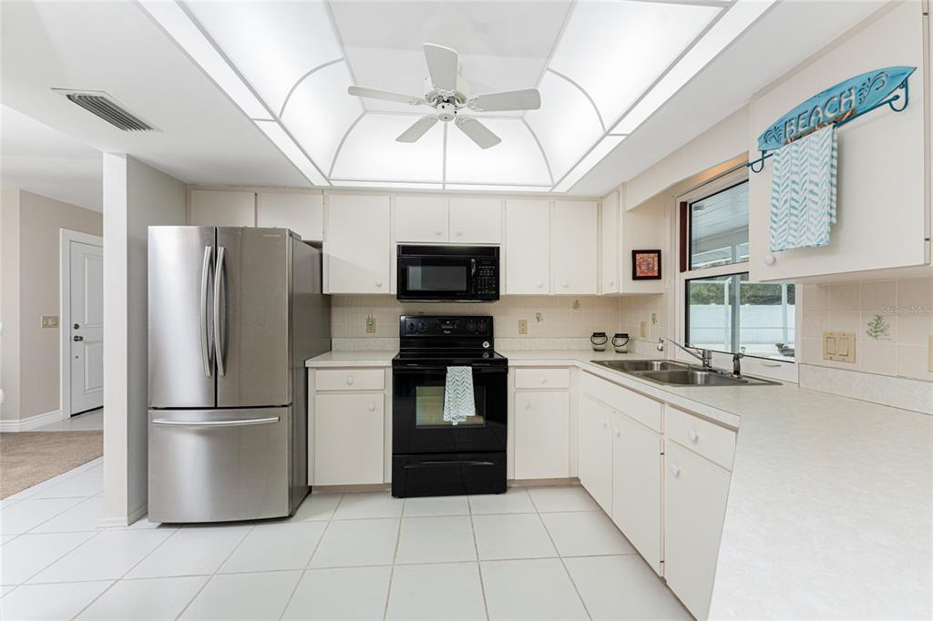 A kitchen features white cabinets, stainless steel appliances, a black stove, and a ceiling fan — 1600 THOMAS STREET, ENGLEWOOD, FL