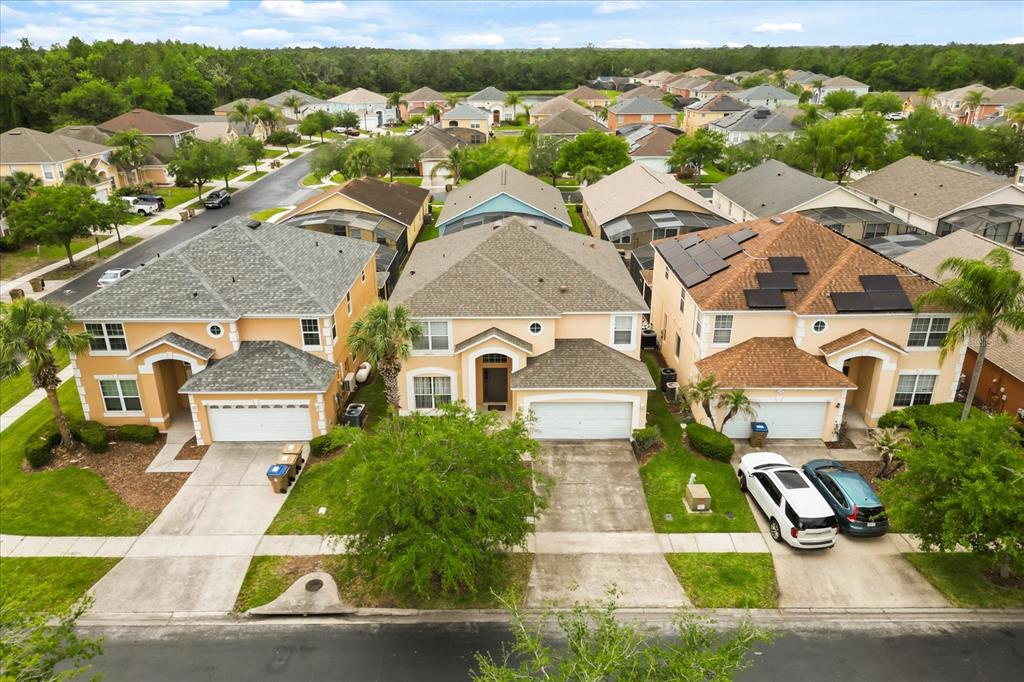 An aerial view shows three suburban houses with driveways and lawns in a residential neighborhood — 164 CASTAWAY BEACH WAY, KISSIMMEE, FL