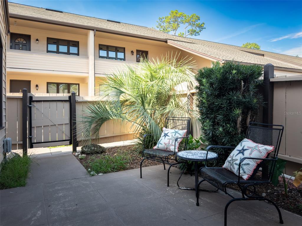 A concrete patio features two metal chairs with starfish pillows and a small table — 2446 NE 7TH ST UNIT 57, OCALA, FL