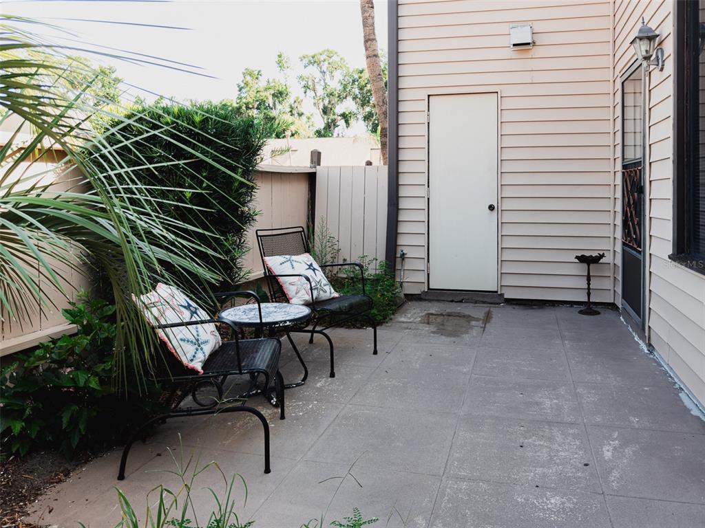 A small concrete patio features two metal chairs with starfish pillows and a side table — 2446 NE 7TH ST UNIT 57, OCALA, FL
