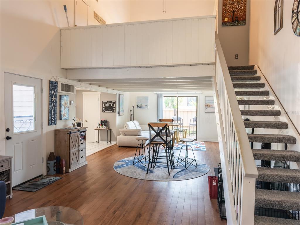 A living area with wood floors, a loft, and a staircase leading to an upper level — 2446 NE 7TH ST UNIT 57, OCALA, FL