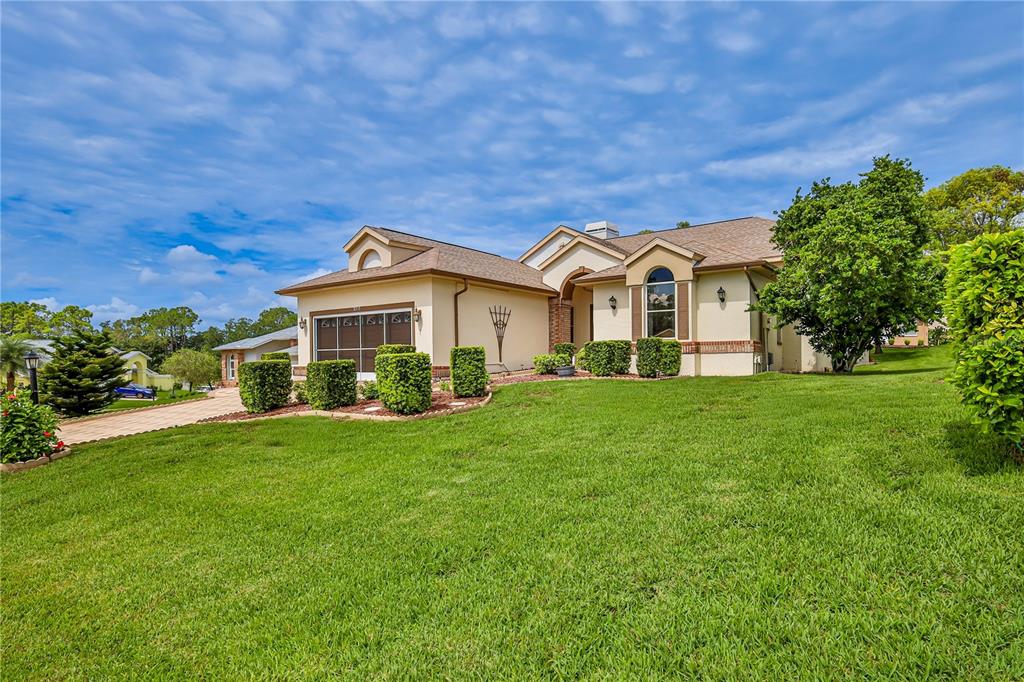 A single-story house with a tan exterior, a two-car garage, and a large front lawn — 2317 SCENIC HILL DRIVE, SPRING HILL, FL