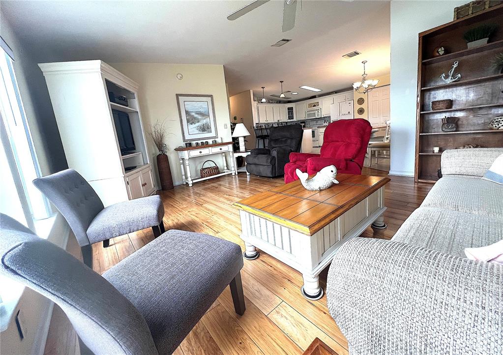 A living room features wood flooring, a coffee table, and a view into the kitchen — 817 S GREEN CIRCLE, VENICE, FL