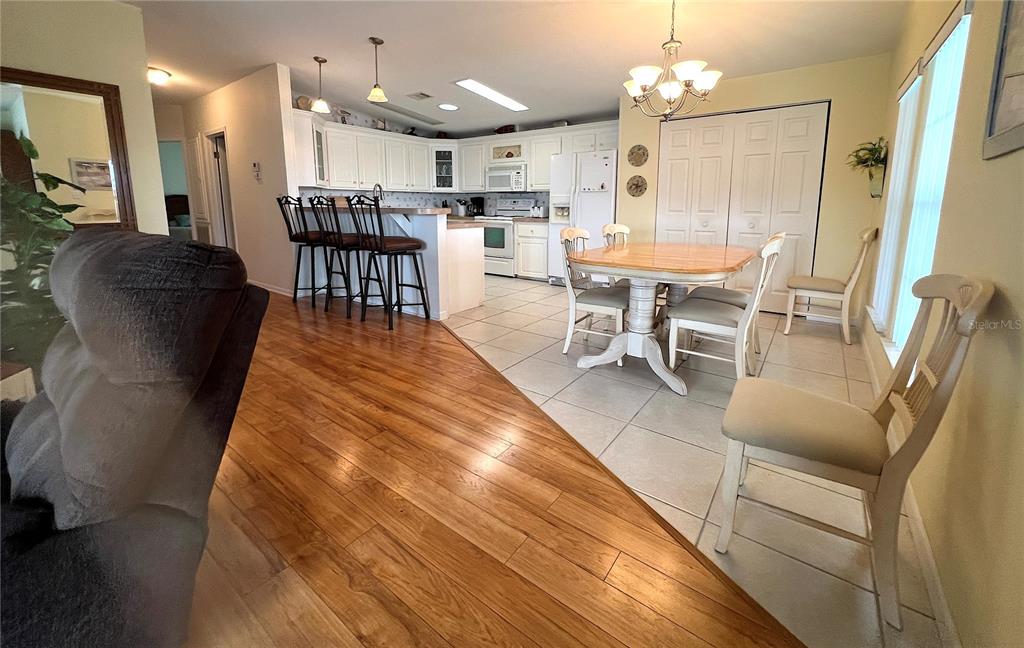 An open-concept kitchen and dining area features wood flooring, tile, and white cabinetry — 817 S GREEN CIRCLE, VENICE, FL