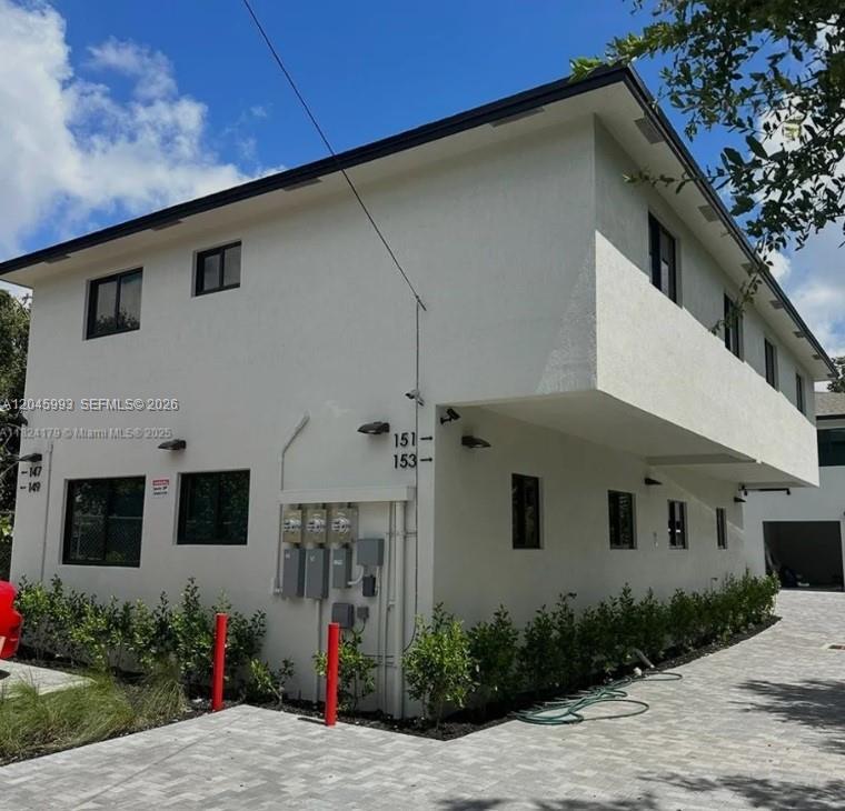 A two-story white stucco building features exterior unit numbers and a paved driveway — 147 NW 61st St, Miami FL 33127, MIAMI, FL