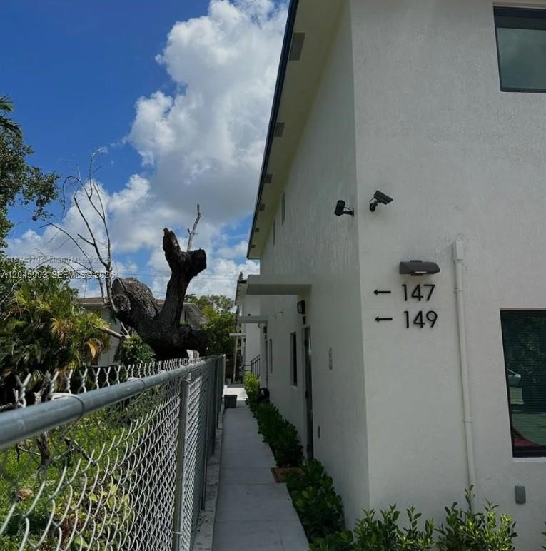 A white building exterior features a walkway, a chain-link fence, and unit numbers 147-149 — 147 NW 61st St, Miami FL 33127, MIAMI, FL