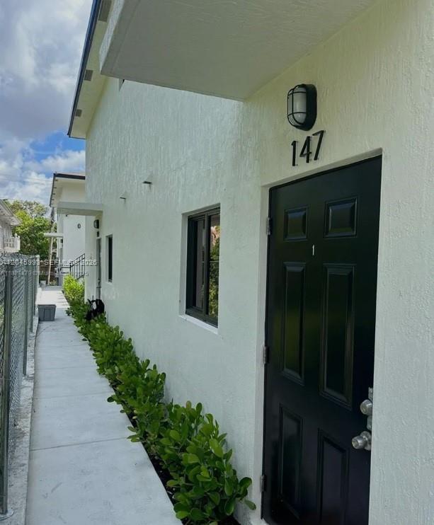 A black front door with the number 147 above it sits beside a concrete walkway — 147 NW 61st St, Miami FL 33127, MIAMI, FL