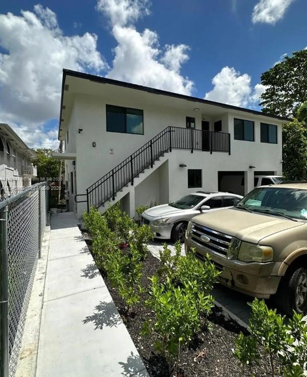 A two-story white building with an exterior staircase and two parked cars in front — 147 NW 61st St, Miami FL 33127, MIAMI, FL