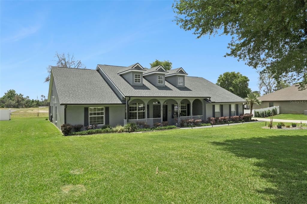 A gray single-story house features a covered front porch and three dormer windows — 31038 FAIRVISTA DRIVE, TAVARES, FL