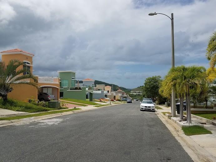 A street view of a residential neighborhood with colorful houses, palm trees, and parked cars — The Village at the Hill MANGO BEACH CORNER UNIT 116, CEIBA, PR