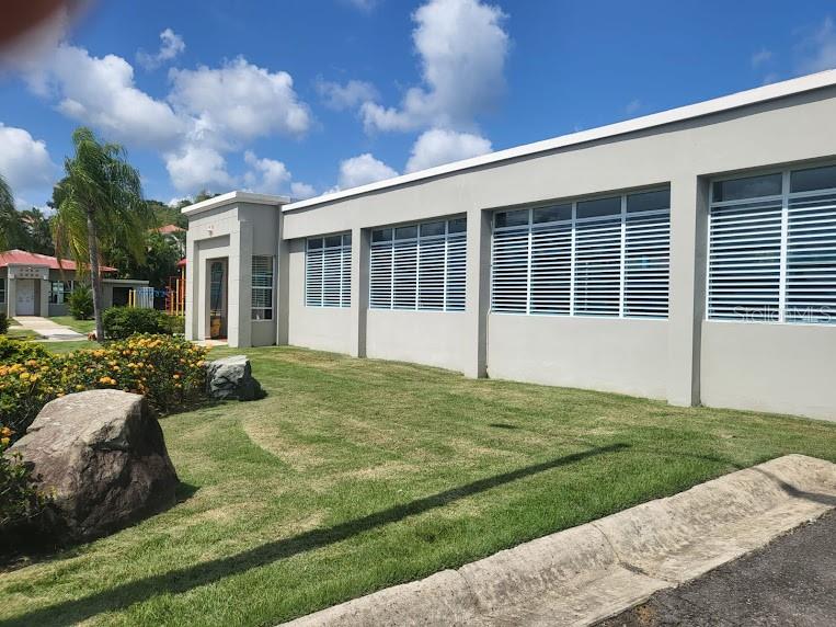 A low-rise building with light gray stucco walls and rows of horizontal window shutters — The Village at the Hill MANGO BEACH CORNER UNIT 116, CEIBA, PR