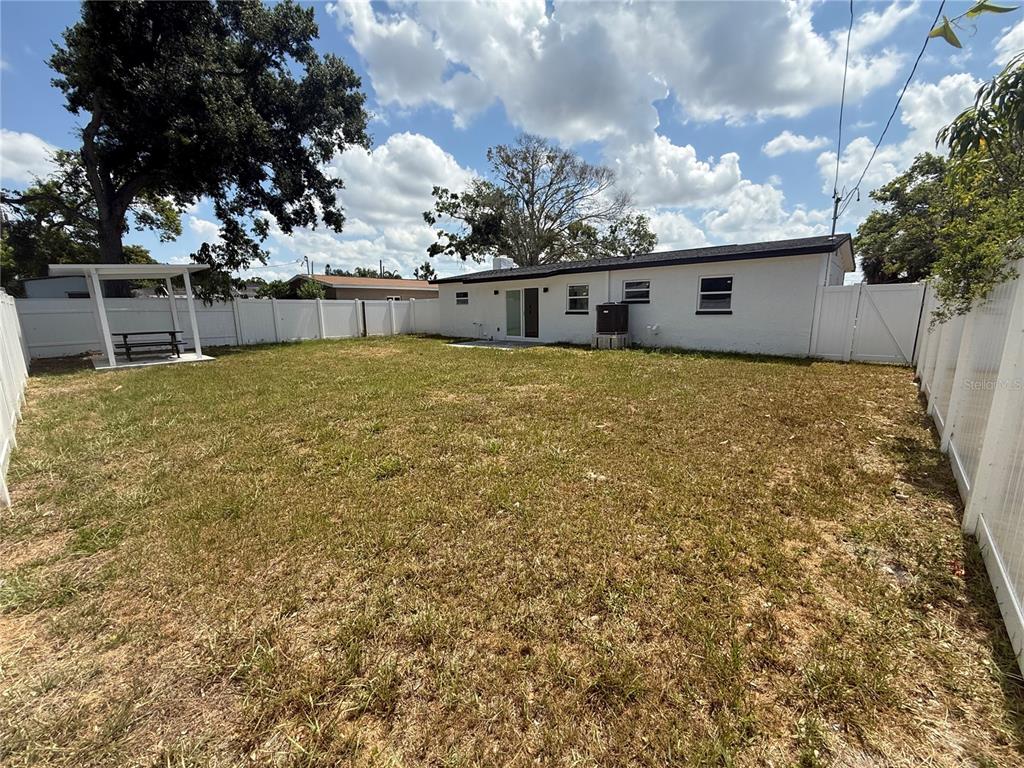A white house with a fenced backyard, a pergola, and a grassy lawn — 4910 HALIFAX DRIVE, TAMPA, FL